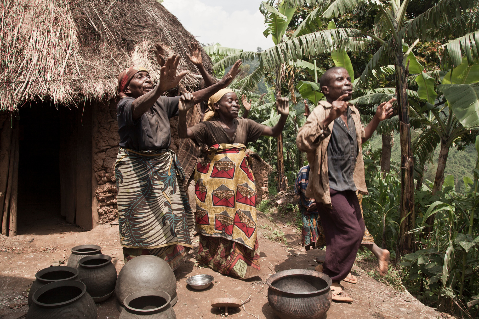 Joyful dance outside a rural hut with lush greenery in the background